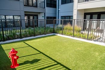 A red fire hydrant sits on a green lawn in front of a building.